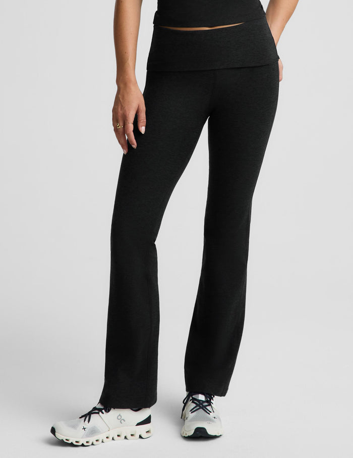 A model wearing black wide-leg athletic pants and white sneakers, shown from the waist down against a light gray studio background.