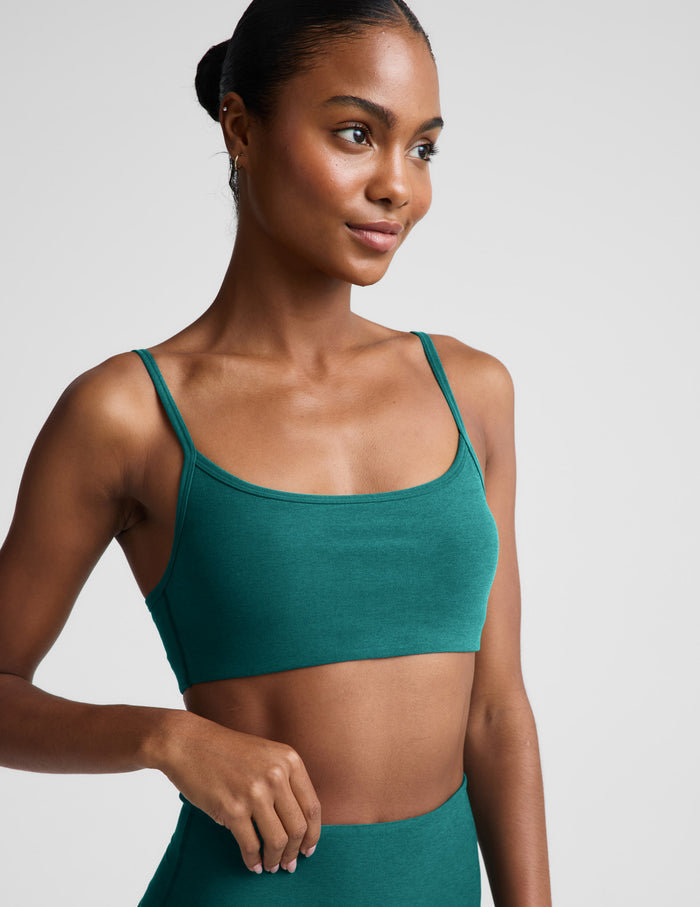 Woman wearing a green sports bra and leggings against a plain background.
