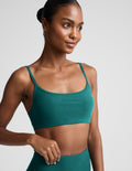 Woman wearing a green sports bra and leggings against a plain background.