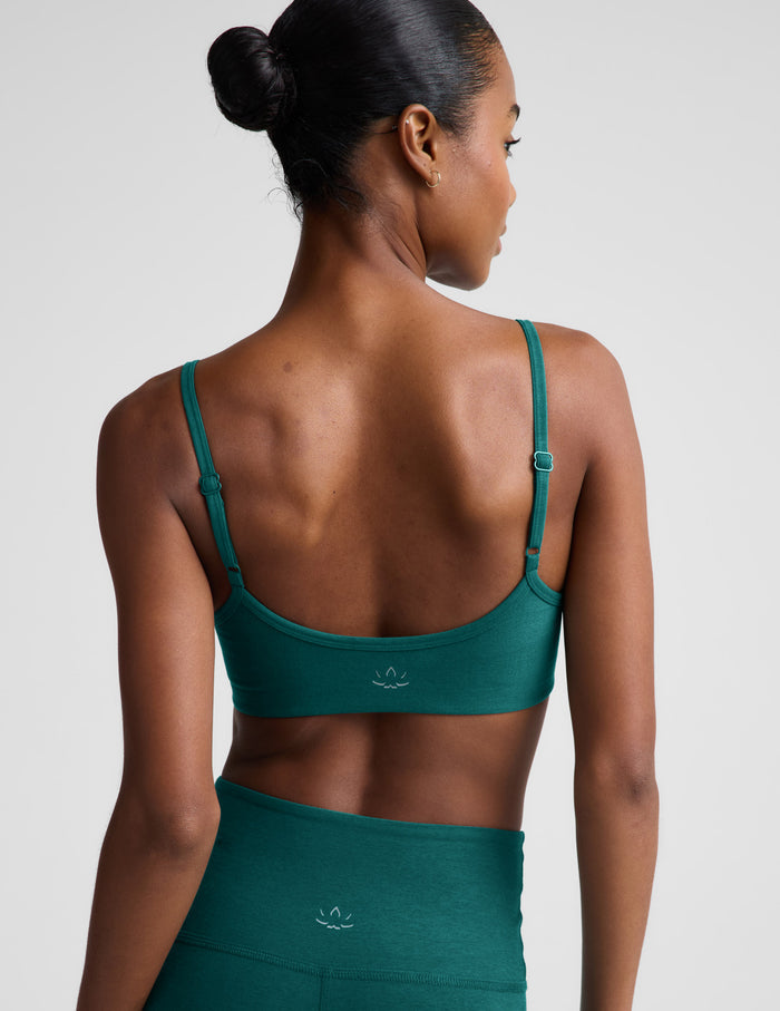 Woman wearing a green sports bra and leggings against a plain background.