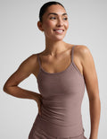 Woman wearing a brown tank top against a plain background.