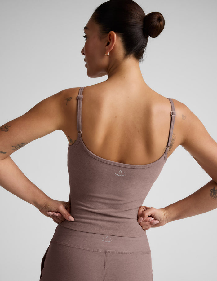 Woman wearing a brown tank top against a plain background.