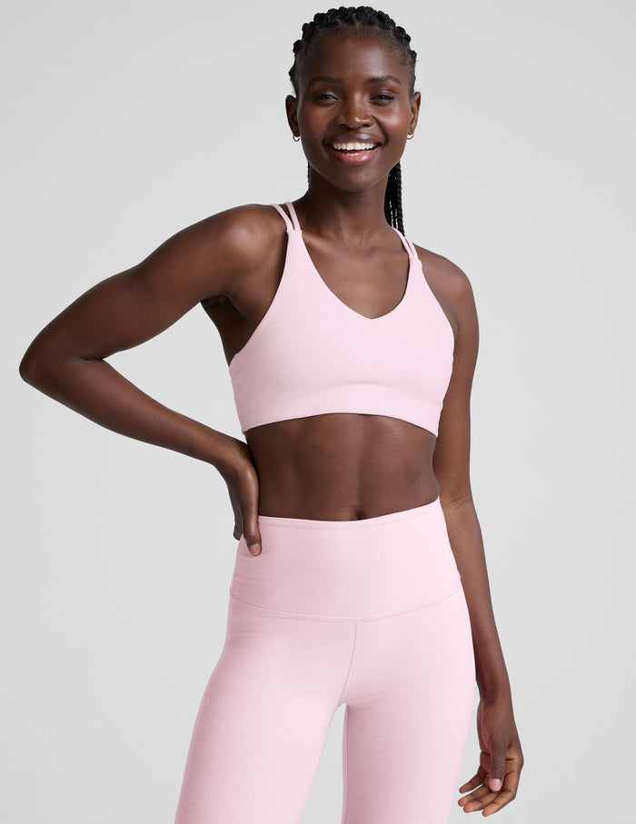 Woman wearing a pink sports bra and leggings on a plain background