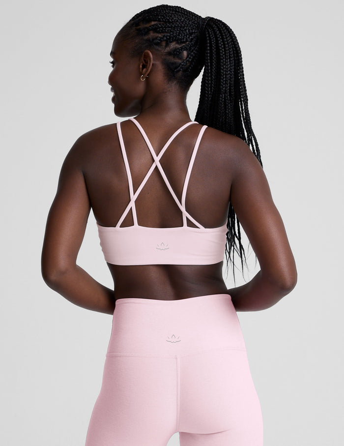 Person wearing a pink sports bra and leggings set on a light gray background
