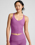 Woman wearing a purple tank top and leggings against a plain background.