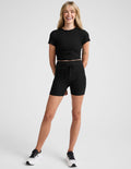 Smiling woman wearing black Spacedye Go Pocket 5" Short featuring a high waistband with drawstring and side pockets.