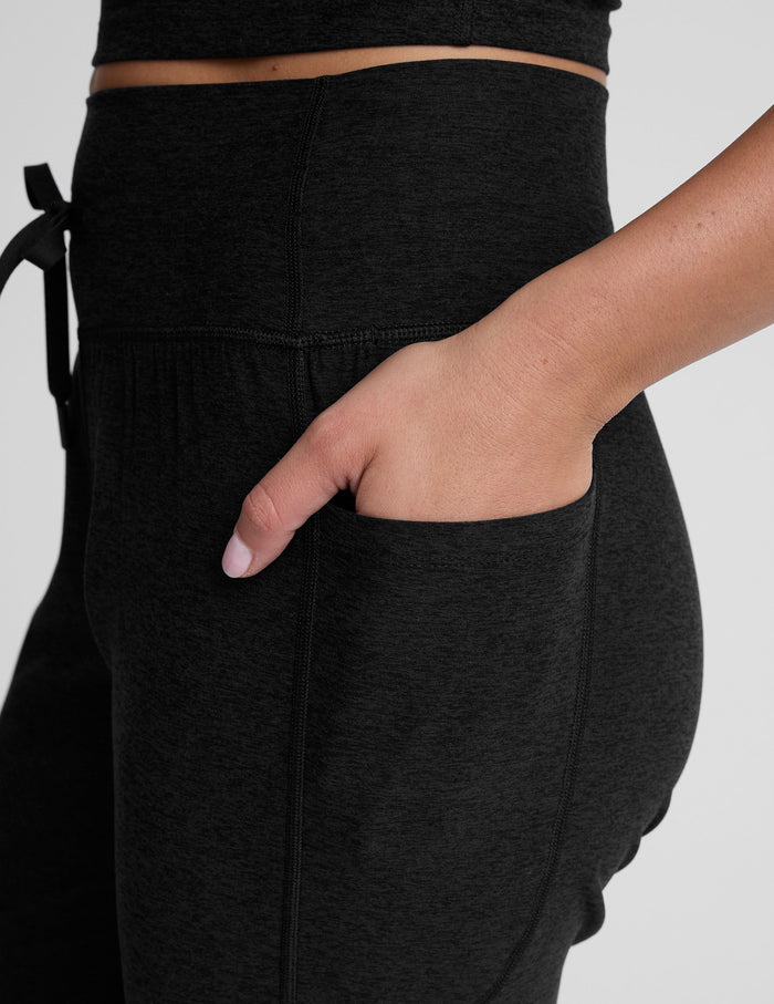 Side view of the black Spacedye Go Pocket Jogger showing the high waistband, drawstring, and a hand in the side pocket.