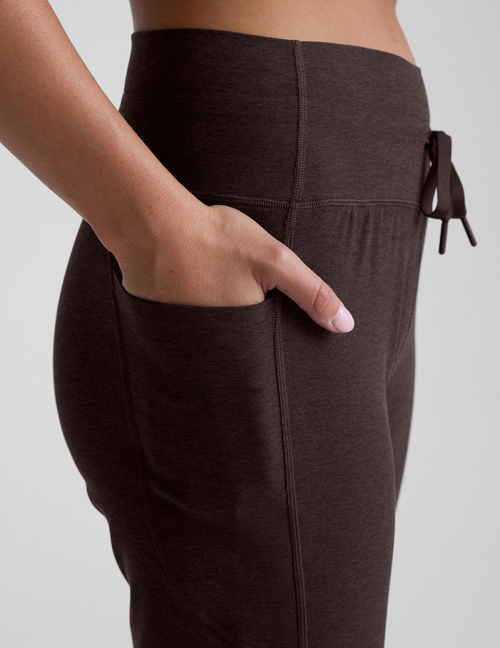 Side view of dark brown Spacedye Go Pocket Jogger featuring high waistband, drawstring tie, and hand in a side pocket.