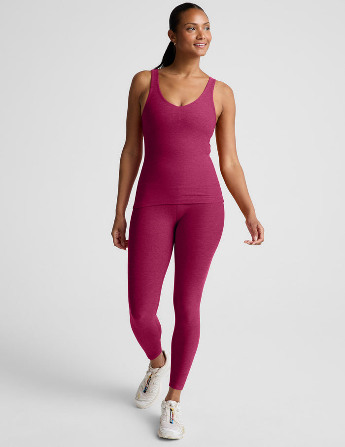 Woman wearing a red full length tank top and leggings against a plain background.