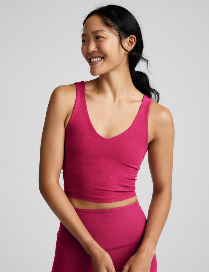 Woman wearing a red cropped v-neck tank and leggings against a plain background.
