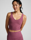 Woman wearing a v-neck cropped tank and leggings against a plain background.