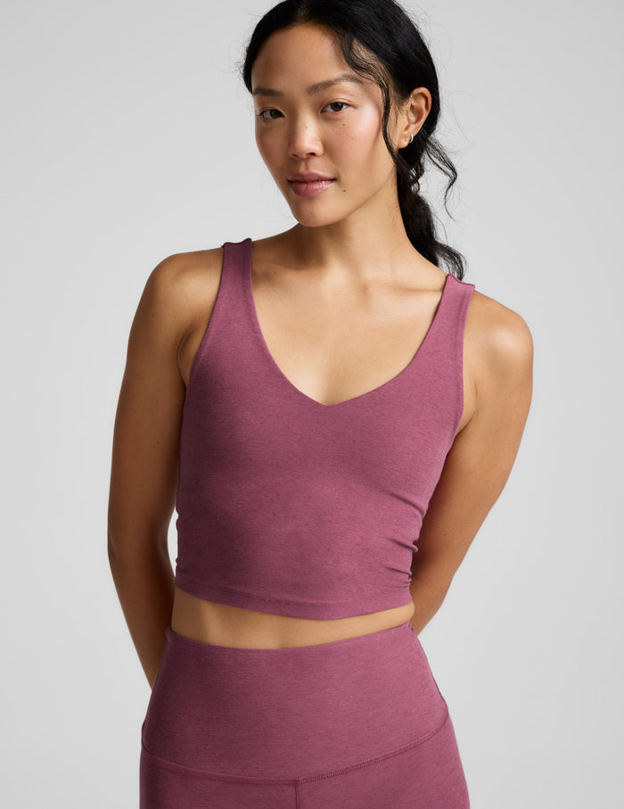 Woman wearing a v-neck cropped tank and leggings against a plain background.