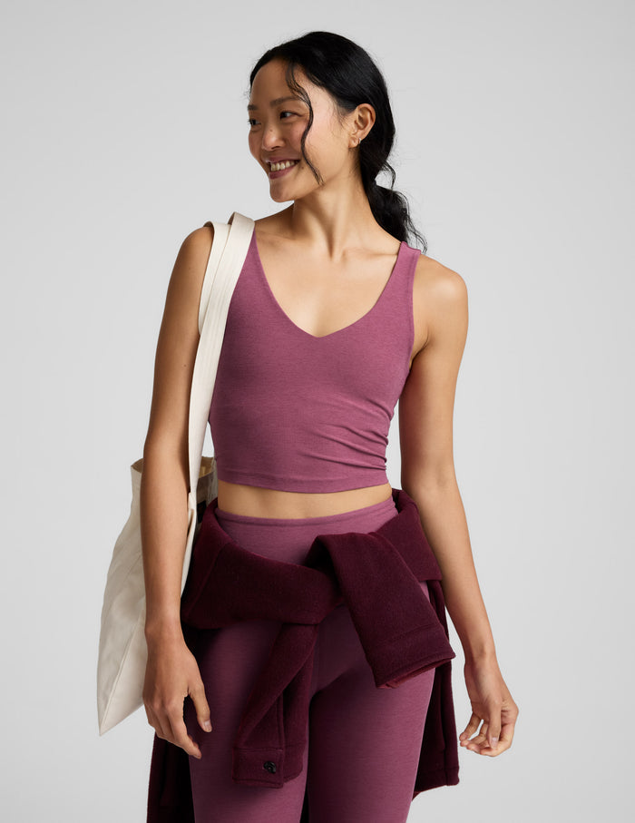 Woman wearing a v-neck cropped tank and leggings against a plain background.