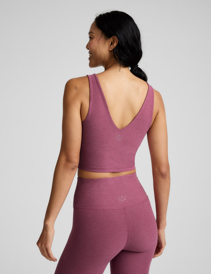 Woman wearing a v-neck cropped tank and leggings against a plain background.