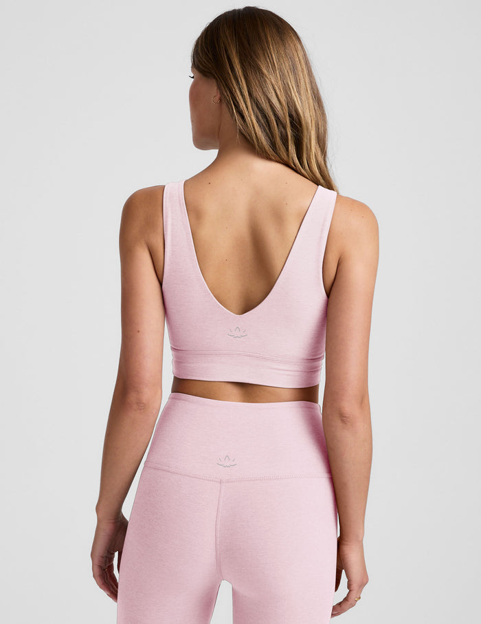 Woman wearing a pink sports bra and leggings set on a light gray background