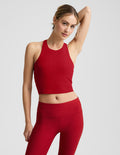 Woman wearing a red high neck racerback cropped tank on a light gray background.