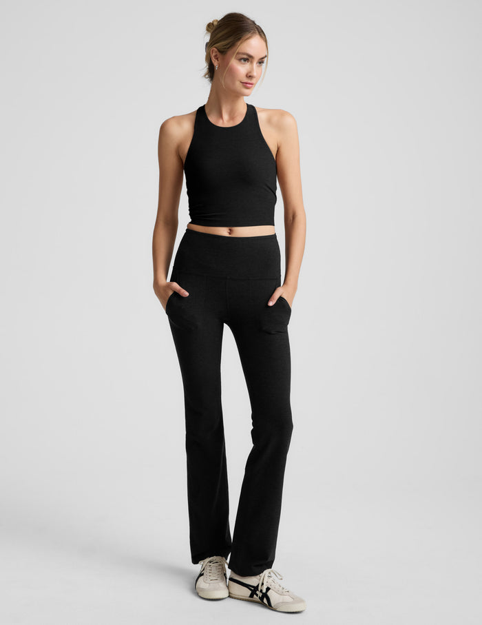 Woman wearing a black high-neck racerback cropped tank against a plain background.