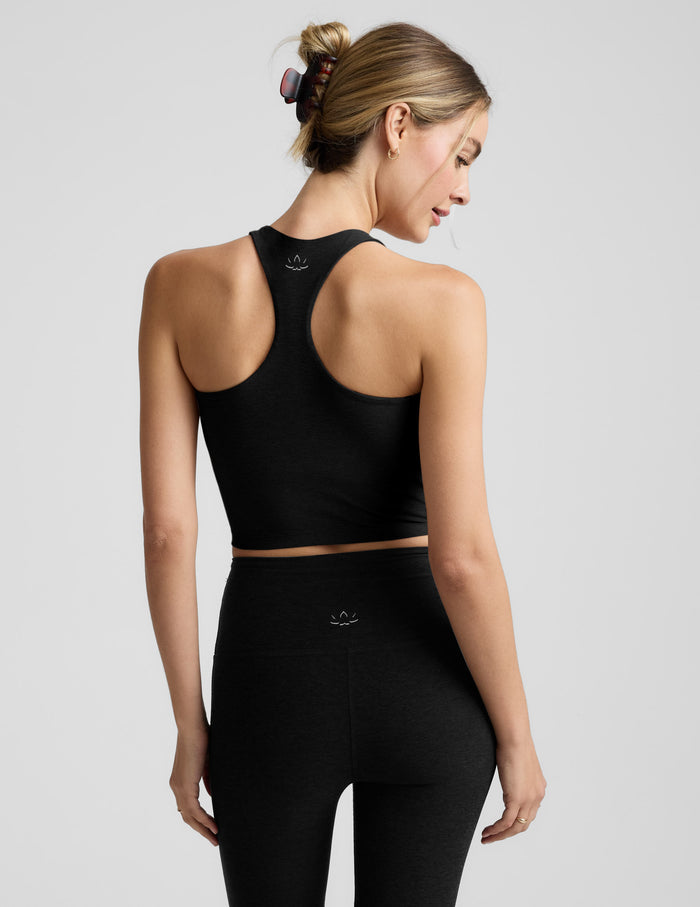 Woman wearing a black high-neck racerback cropped tank against a plain background.