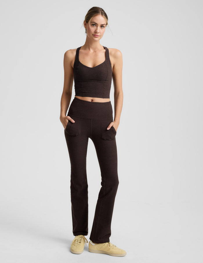 Woman wearing a brown v-neck racerback cropped tank and leggings on a light gray background.