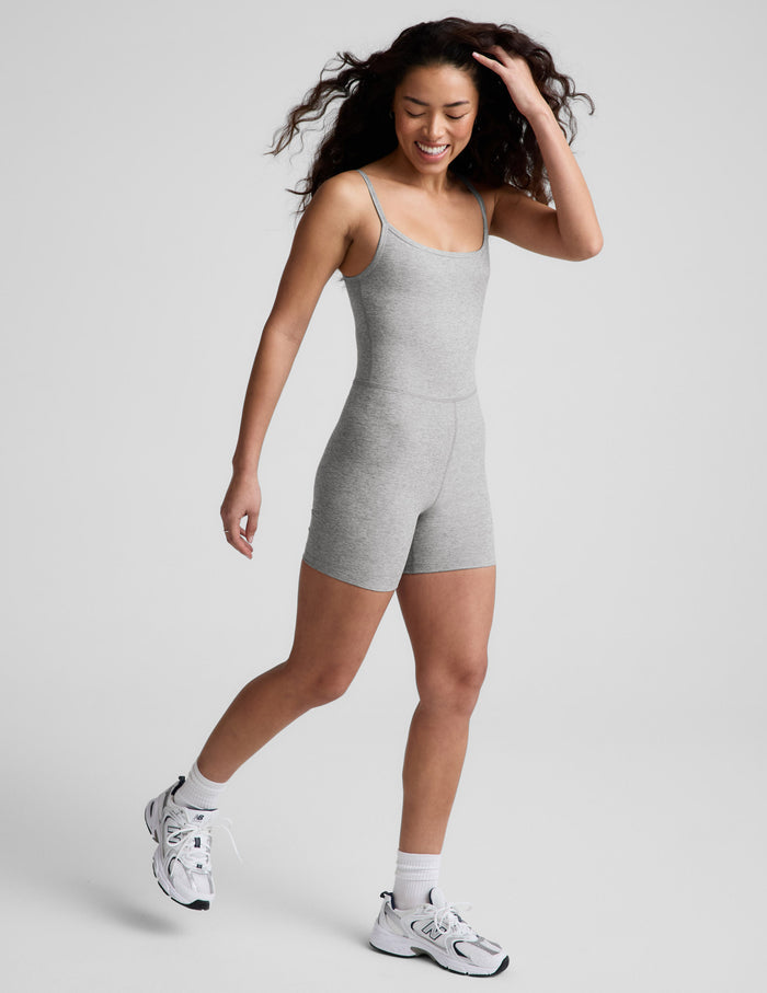 Woman wearing a gray short bodysuit against a plain background.