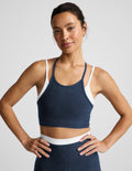 Woman wearing a navy layered bra and leggings against a plain background.