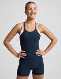 A woman modeling a dark navy blue tank top and matching shorts set against a light gray studio background.