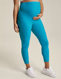 Woman wearing Cali Blue Heather Spacedye Love The Bump Capri Maternity Legging™ paired with white sneakers.