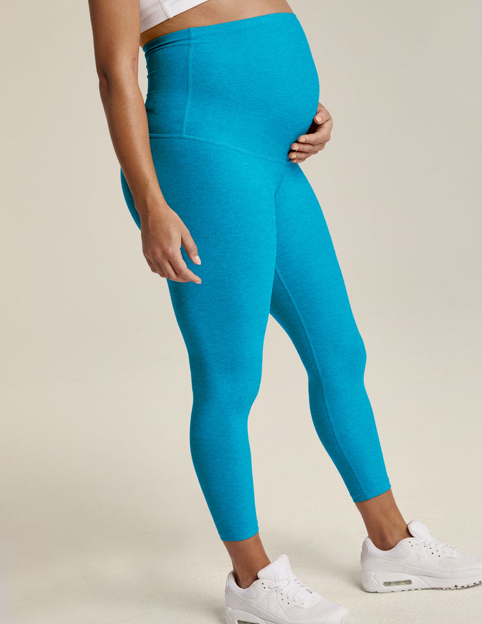 Woman wearing Cali Blue Heather Spacedye Love The Bump Capri Maternity Legging™ with white sneakers, side profile.