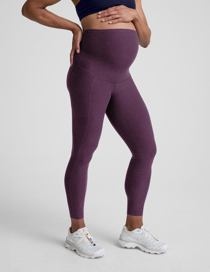 Woman wearing a purple maternity pocket leggings against a plain background.