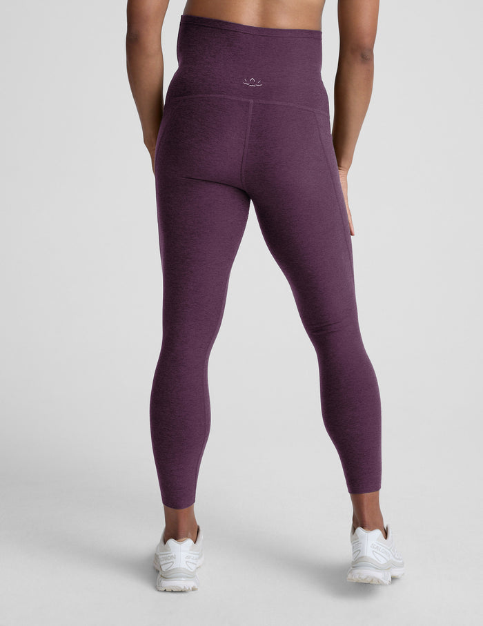 Woman wearing a purple maternity pocket leggings against a plain background.