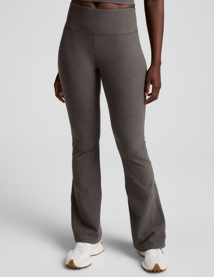 A person wears the dark gray marled Spacedye Mid-Rise Bootcut Pant featuring a wide waistband and flared hem.