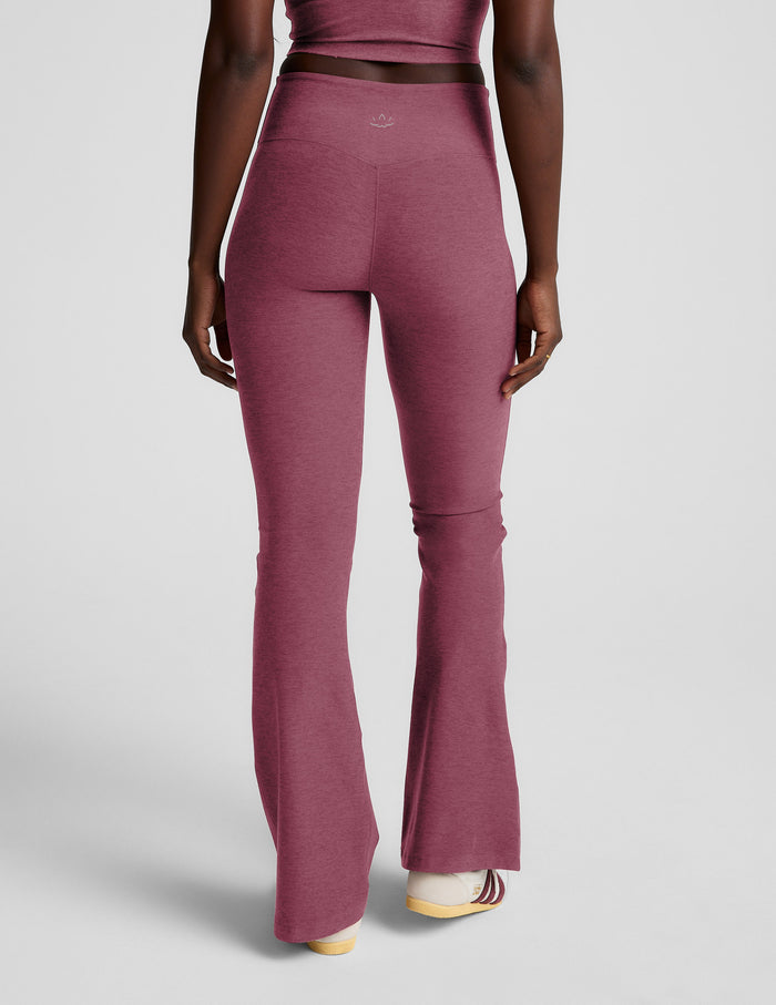 Rear view of the blush Spacedye Mid-Rise Bootcut Pant, featuring a snug fit through the leg and a flared hem.