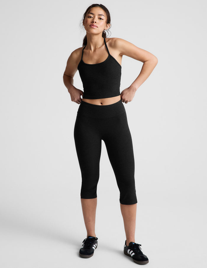 Model wearing Spacedye Mid-Rise Slit Pedal Pusher Legging in black with a matching tank and sneakers on a white background.