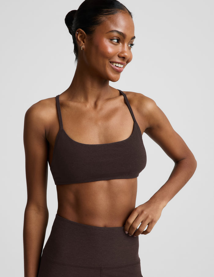 Woman wearing a brown bra and brown leggings against a plain background.