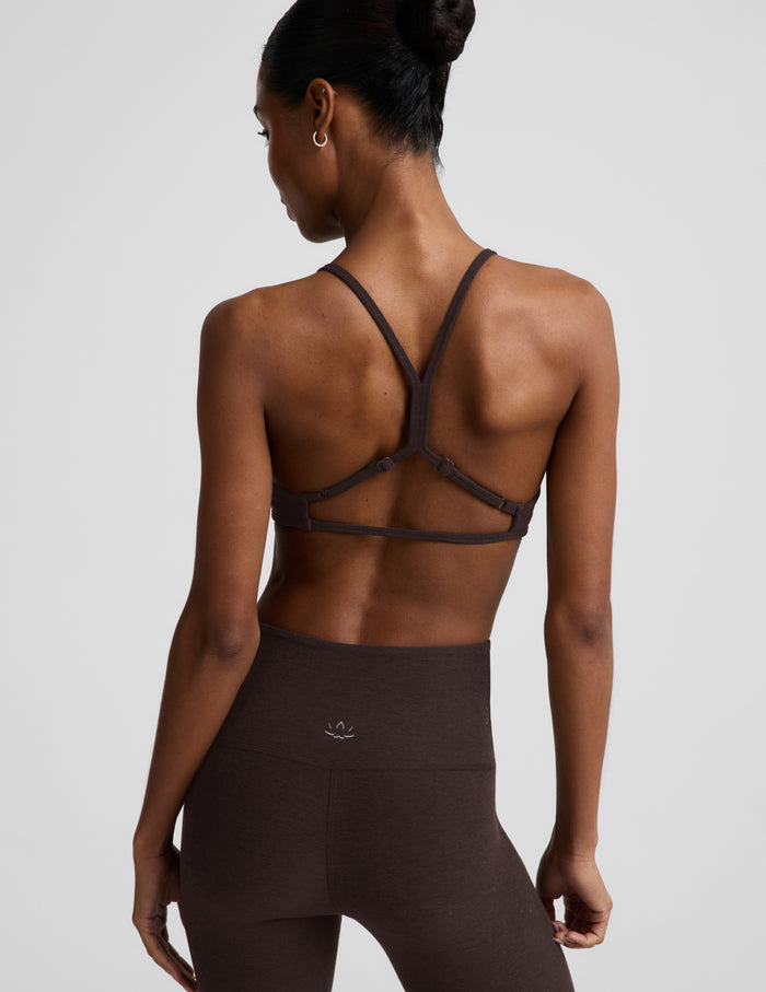 Woman wearing a brown bra and brown leggings against a plain background.