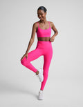 Woman wearing a bright pink athletic outfit on a light gray background.