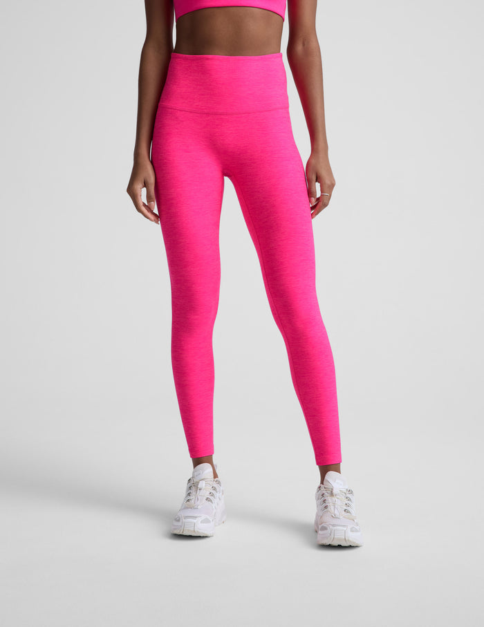 Woman wearing a bright pink athletic outfit on a light gray background.