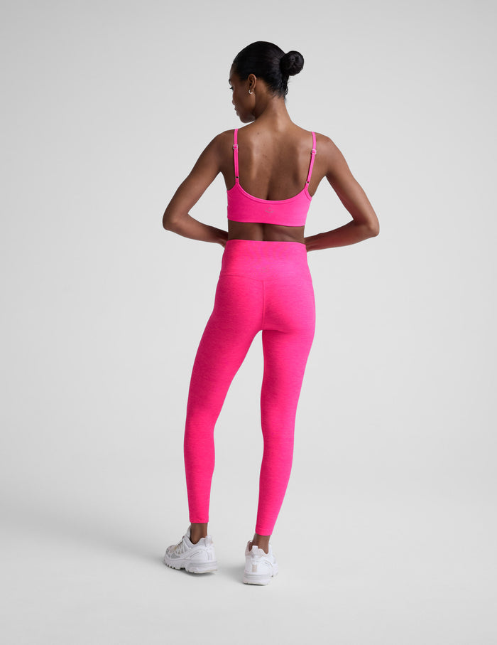 Woman wearing a bright pink athletic outfit on a light gray background.