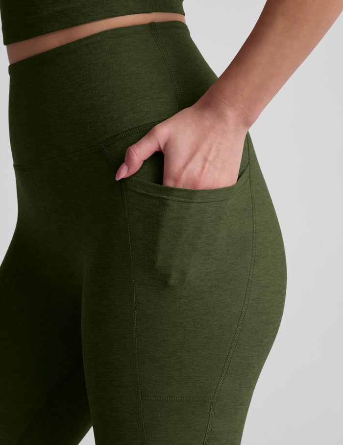 Close-up of olive Spacedye Out Of Pocket High Waisted Capri Legging with a hand resting in the side hip pocket.