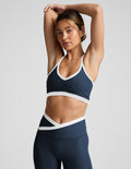 Woman wearing a navy sports bra and leggings with white accents on a light gray background.