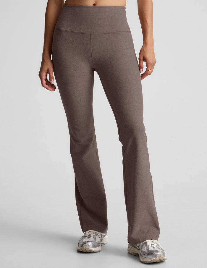 woman wearing brown high-waisted bootcut pants against a plain background.