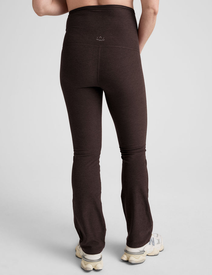 Rear view of woman wearing Brown Spacedye Practice Maternity Pant™ with flare leg, paired with cream sneakers.