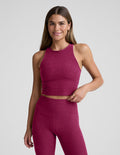 Woman wearing a red high-neck cropped tank and leggings against a plain background.