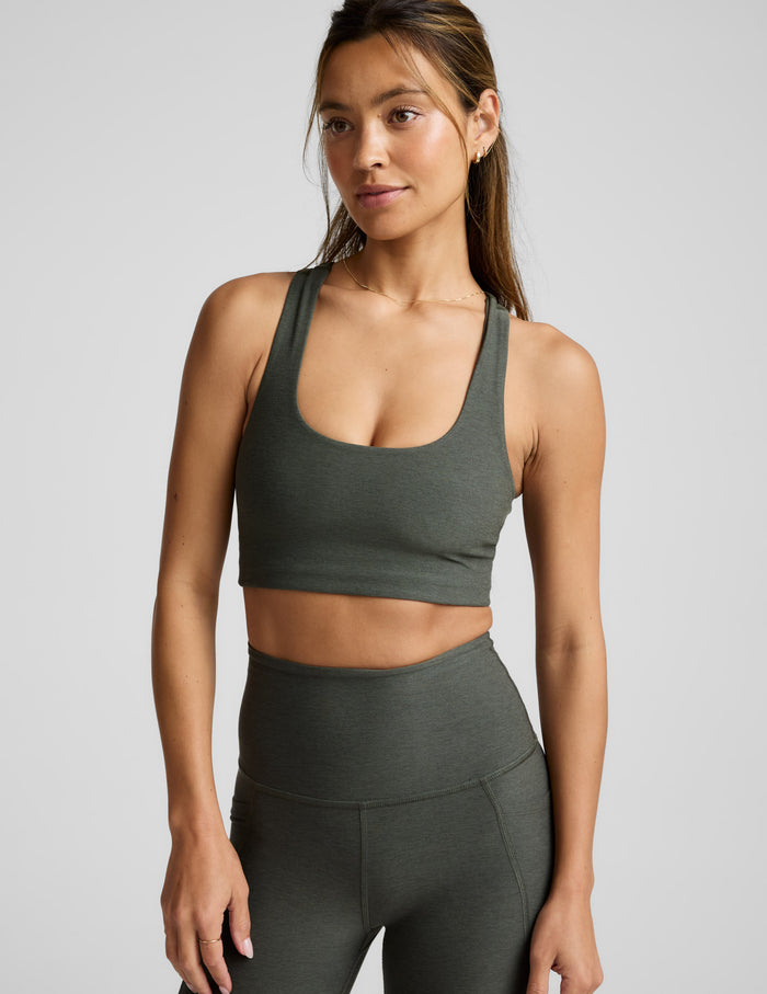 Woman wearing a green bra and leggings on a light gray background.