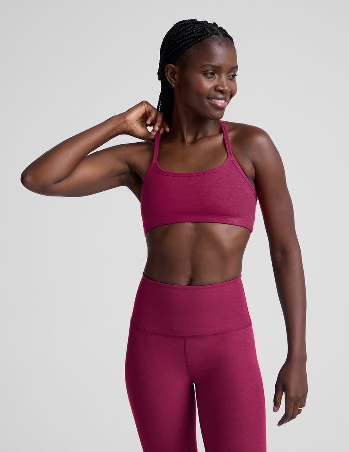 Woman wearing a red sports bra and leggings on a light gray background.