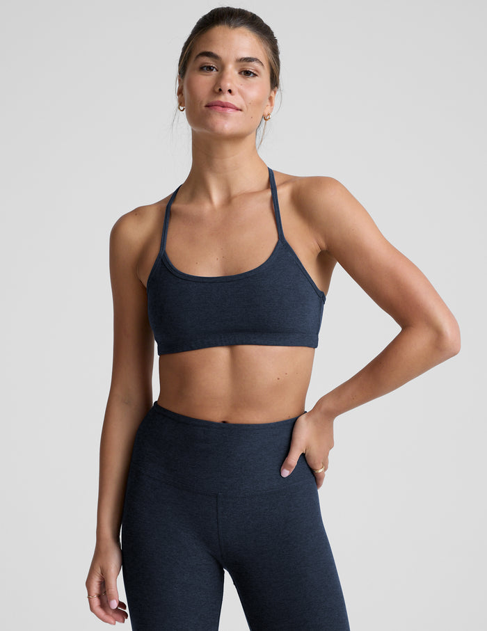 Woman wearing a navy sports bra and leggings against a plain background.