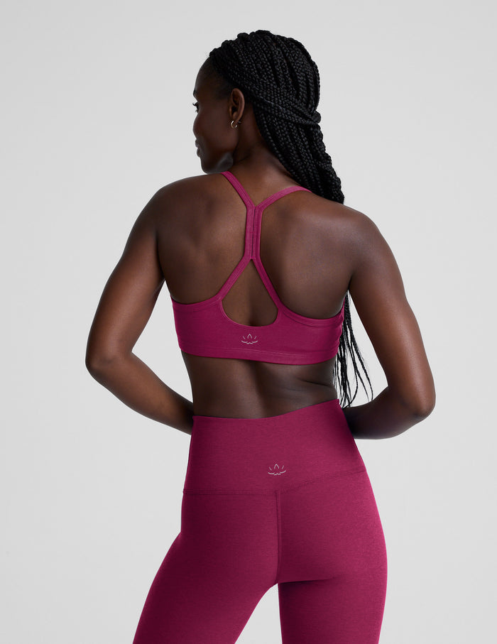 Woman wearing a red sports bra and leggings on a light gray background.