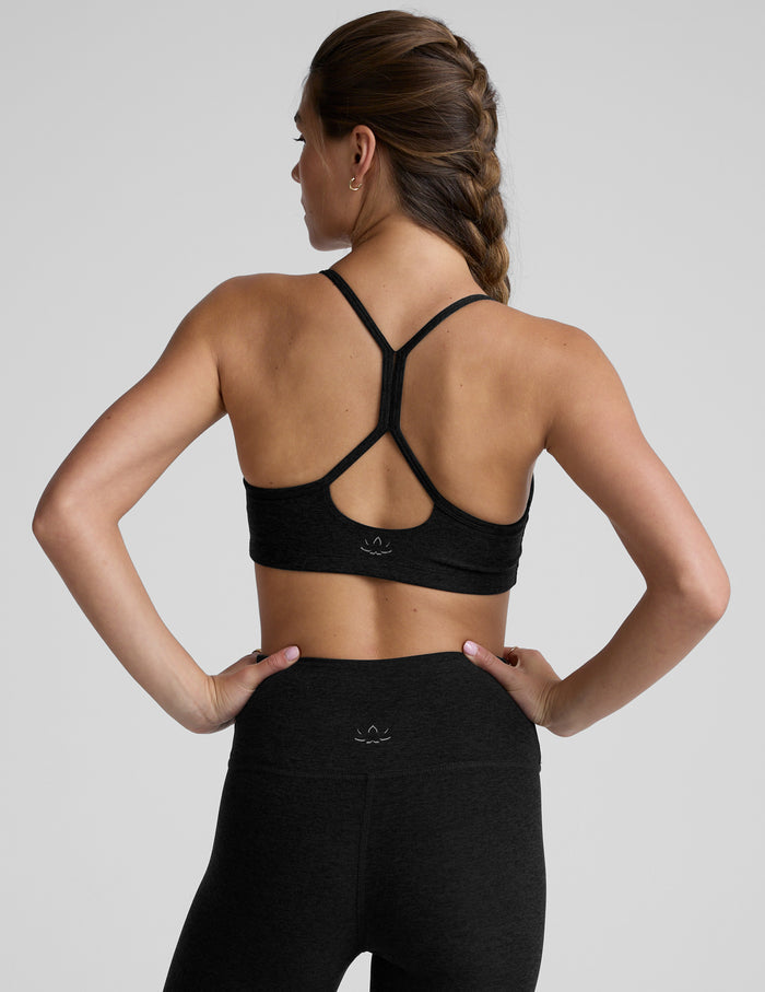 Woman wearing a black sports bra and leggings on a light gray background.