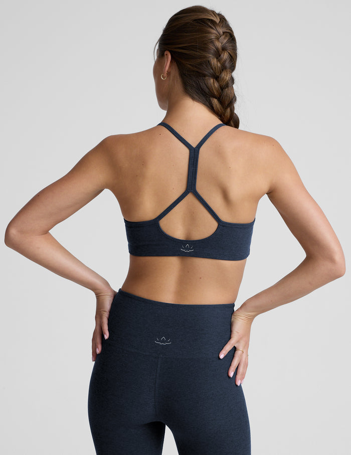 Woman wearing a navy sports bra and leggings against a plain background.