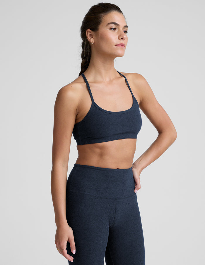 Woman wearing a navy sports bra and leggings against a plain background.